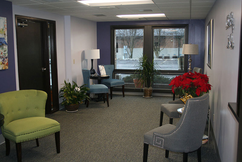 another angle of our waiting room showing grey, green, and blue chairs and a window