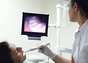 picture of a dentist using an intraoral camera on a patient and looking at the screen