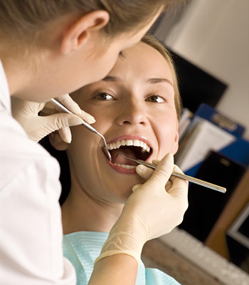 woman in a dental chair getting a checkup by a dentist and smiling
